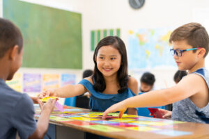 A group of diverse students are sitting in their classroom while working on science projects. They are trying to finish a matching game before time is up.